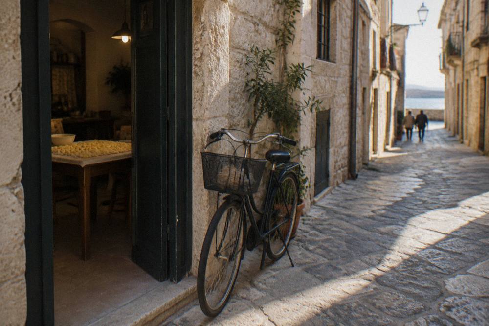 A bicycle leaning at the doorway of an old-town house, a table of fresh pasta visible inside, soft light, Bari Vecchia