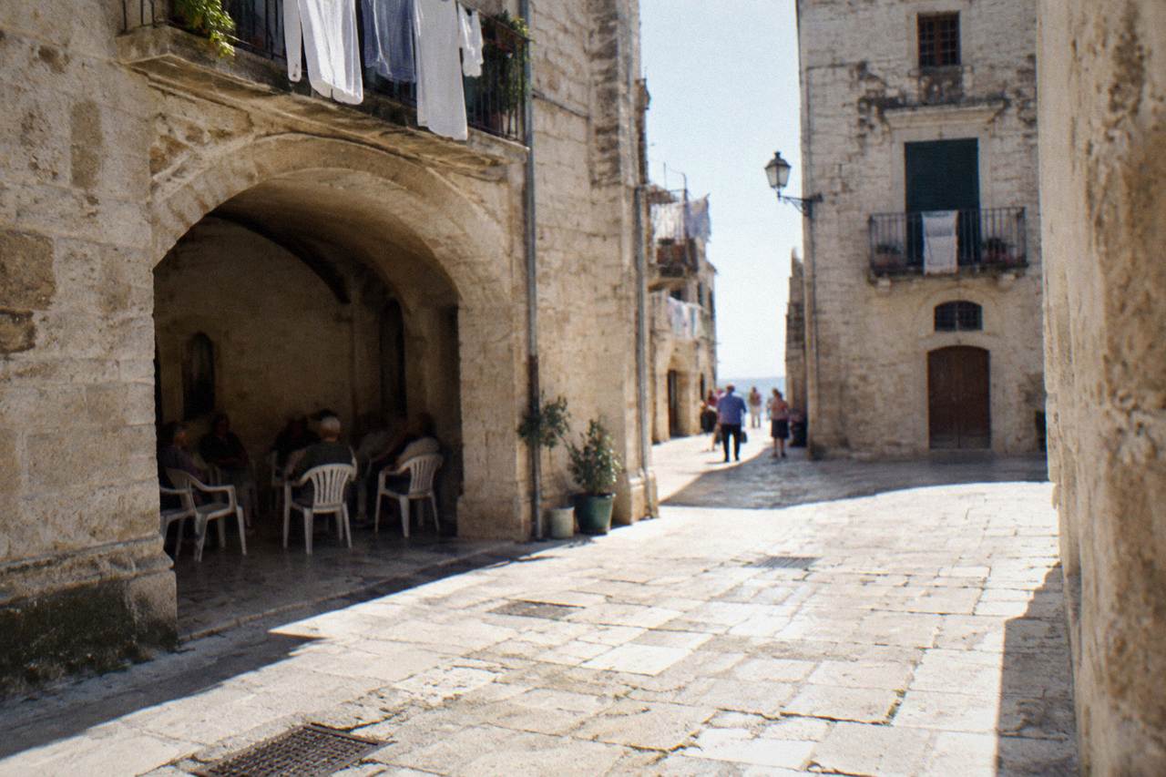Tiny square where plastic chairs are drawn up in a circle and elderly residents chat far off in the shade