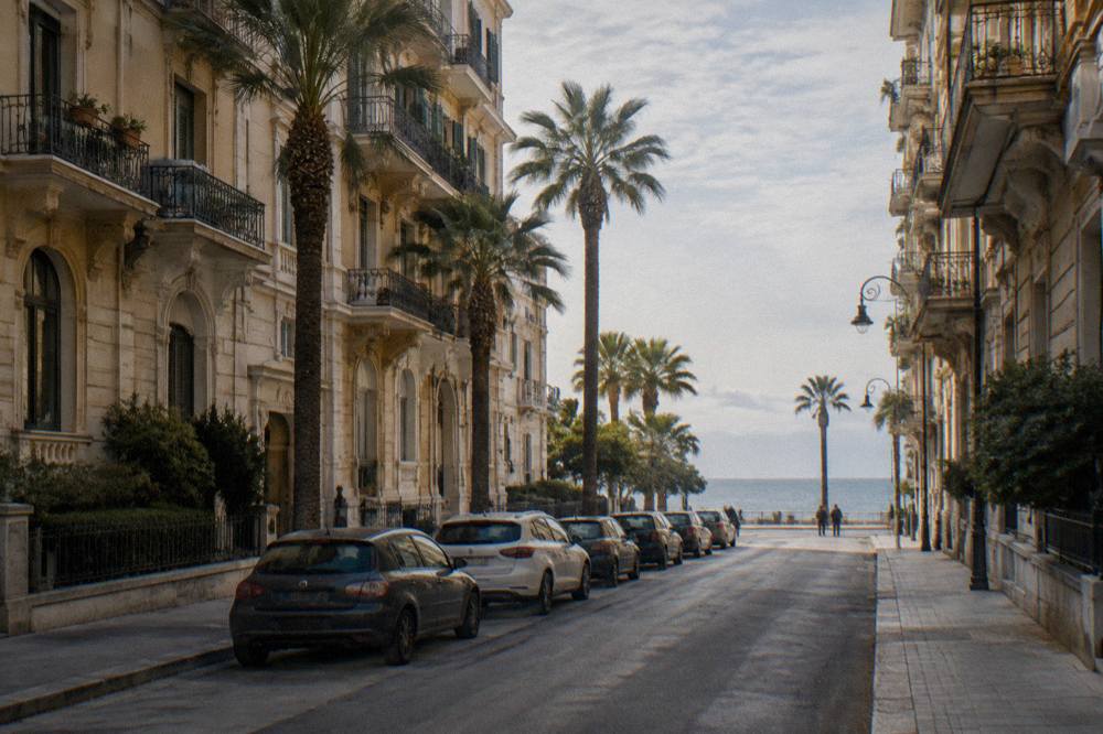 Residential street of Liberty apartment buildings with iron balconies, palm trees and the sea at its end