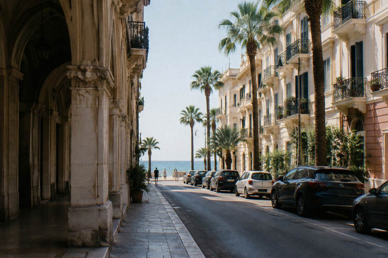 Residential street of Liberty apartment buildings with iron balconies, palm trees and the sea at its end