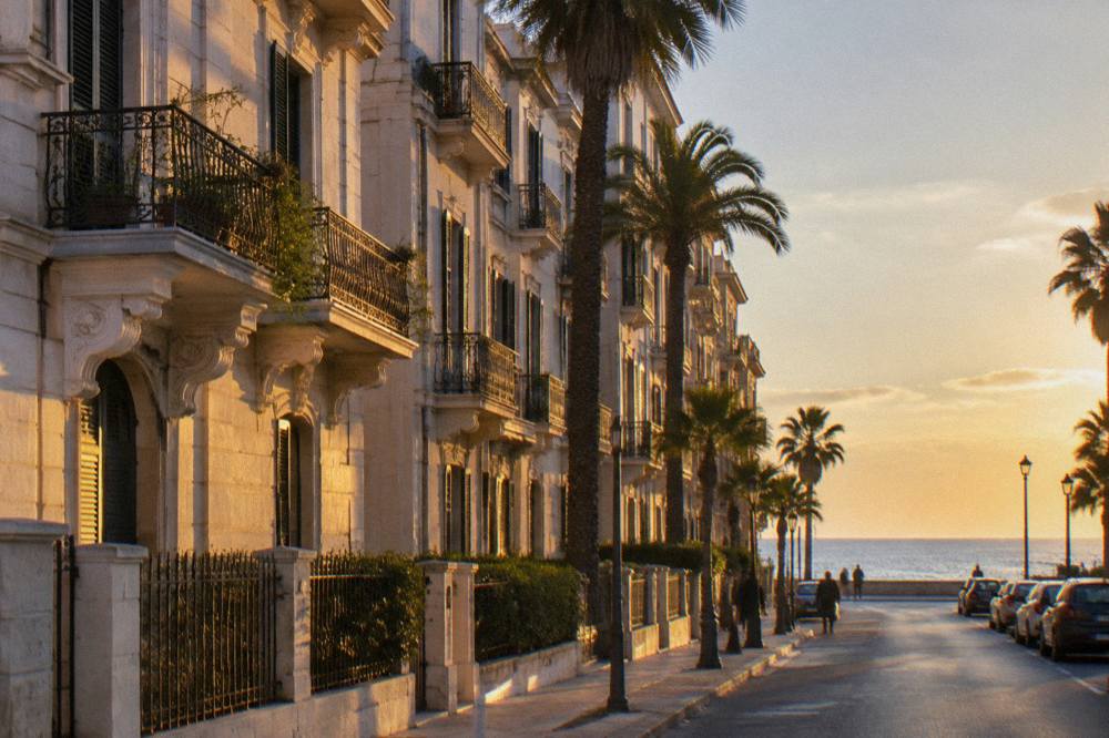 Residential street of Liberty apartment buildings with iron balconies, palm trees and the sea at its end
