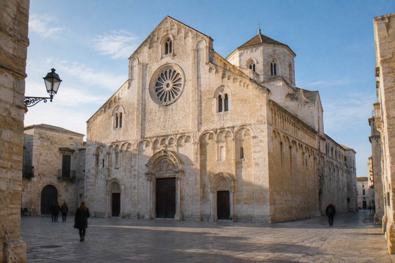 Romanesque cathedral of golden limestone with blind arcading, a wheel window and an octagonal drum dome above a small square