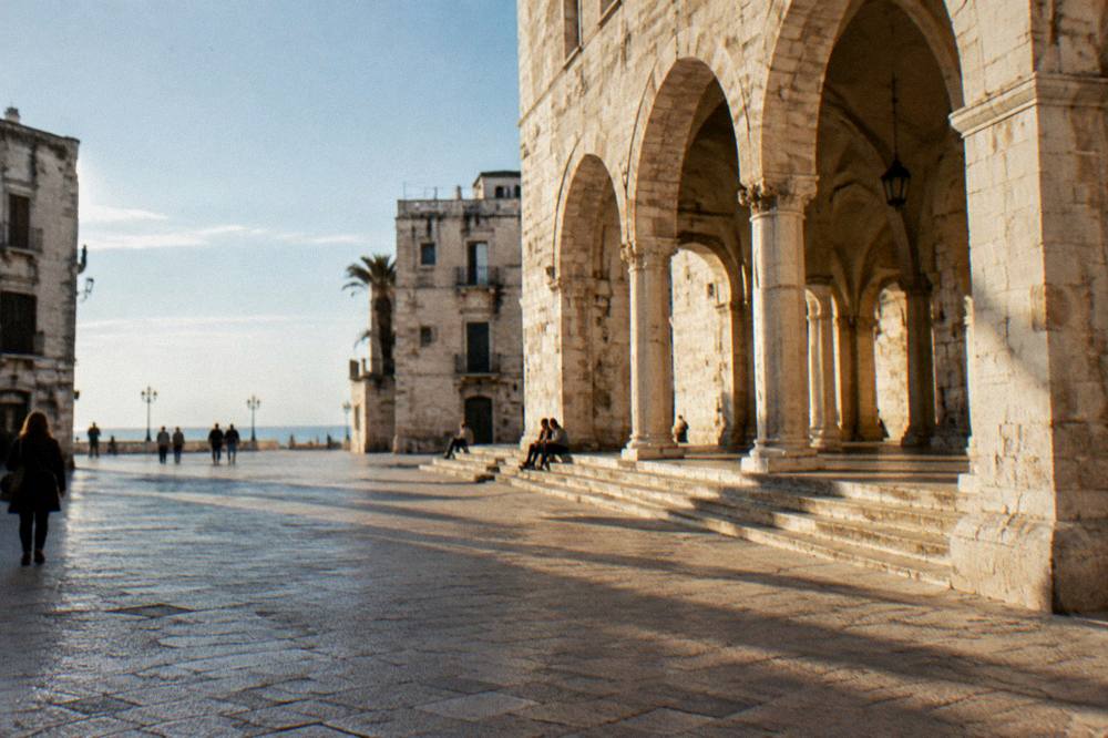 Loggia arches with long afternoon shadows and a few distant people sitting on the steps