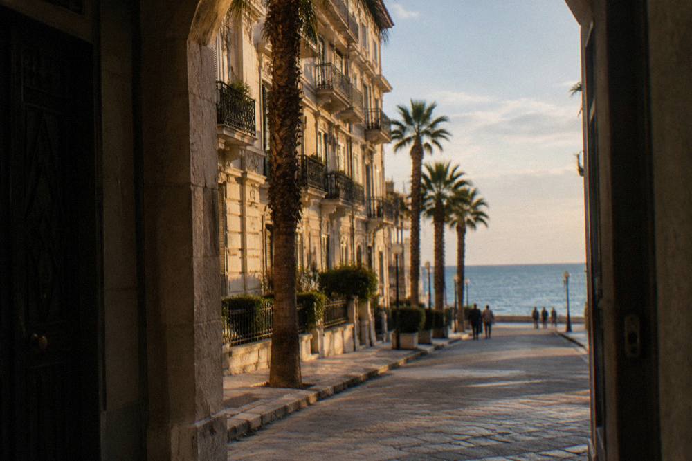 Residential street of Liberty apartment buildings with iron balconies, palm trees and the sea at its end