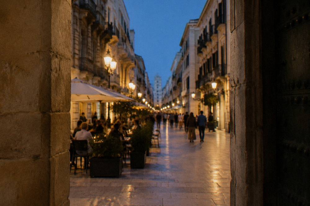 Pedestrian shopping street in the evening with lit lamps, cafe tables and out-of-focus people