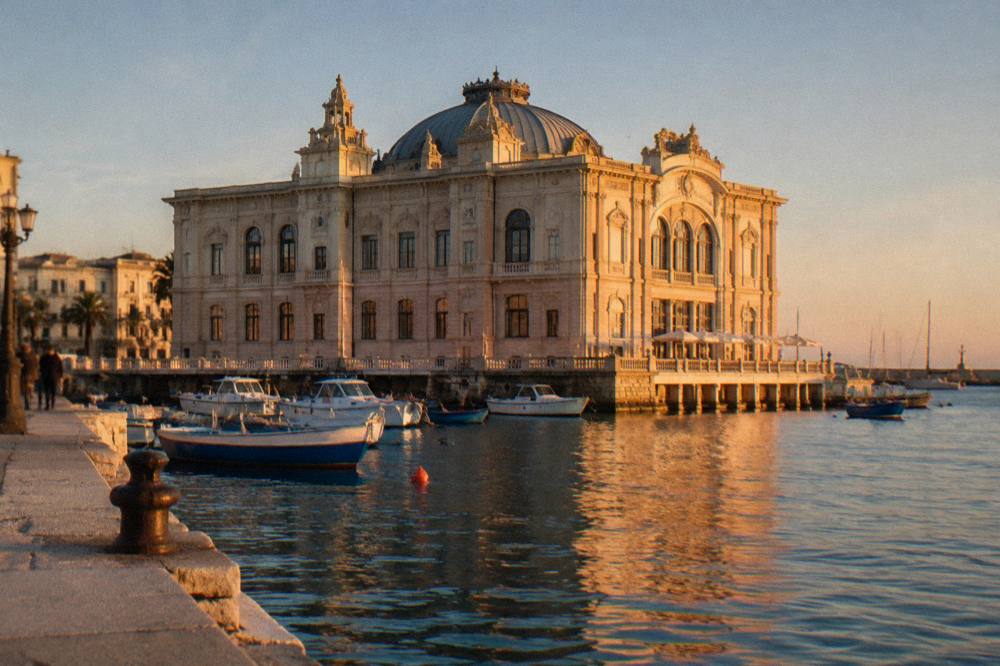 Ornate Liberty-style building standing at the edge of harbour water with boats beside it