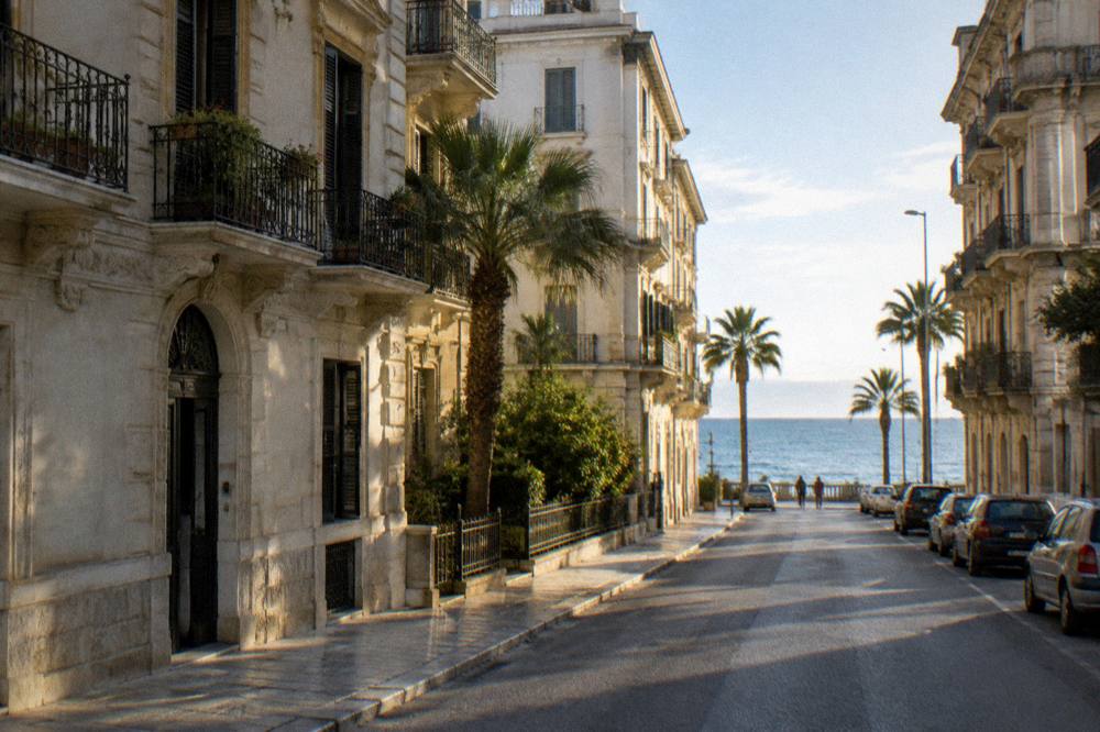 Residential street of Liberty apartment buildings with iron balconies, palm trees and the sea at its end
