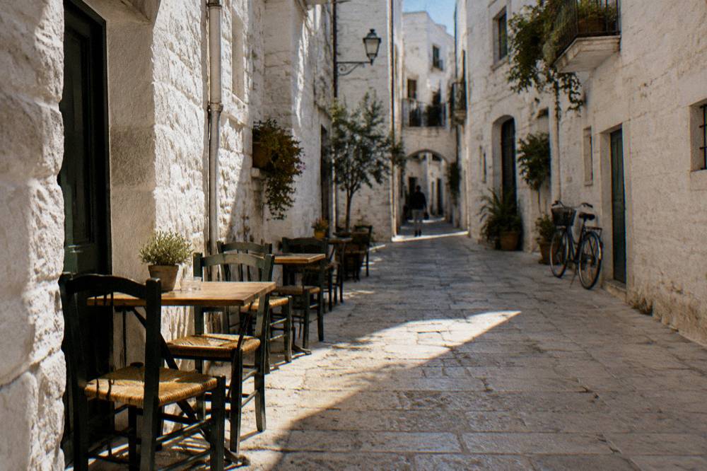 Whitewashed old town lane at midday with chairs and tables against the walls and stripes of sun and shadow