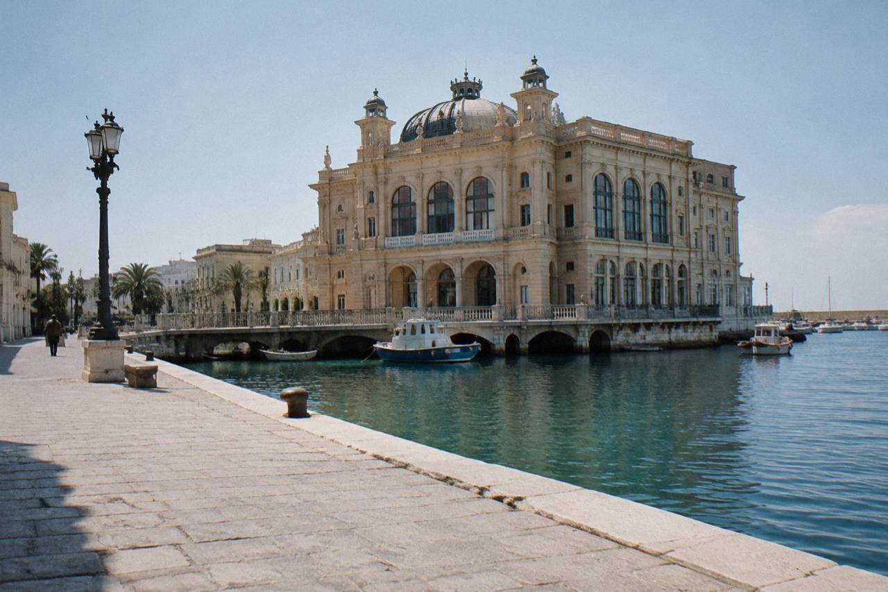 Ornate Liberty-style building standing at the edge of harbour water with boats beside it