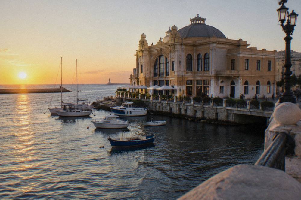 Ornate Liberty-style building standing at the edge of harbour water with boats beside it