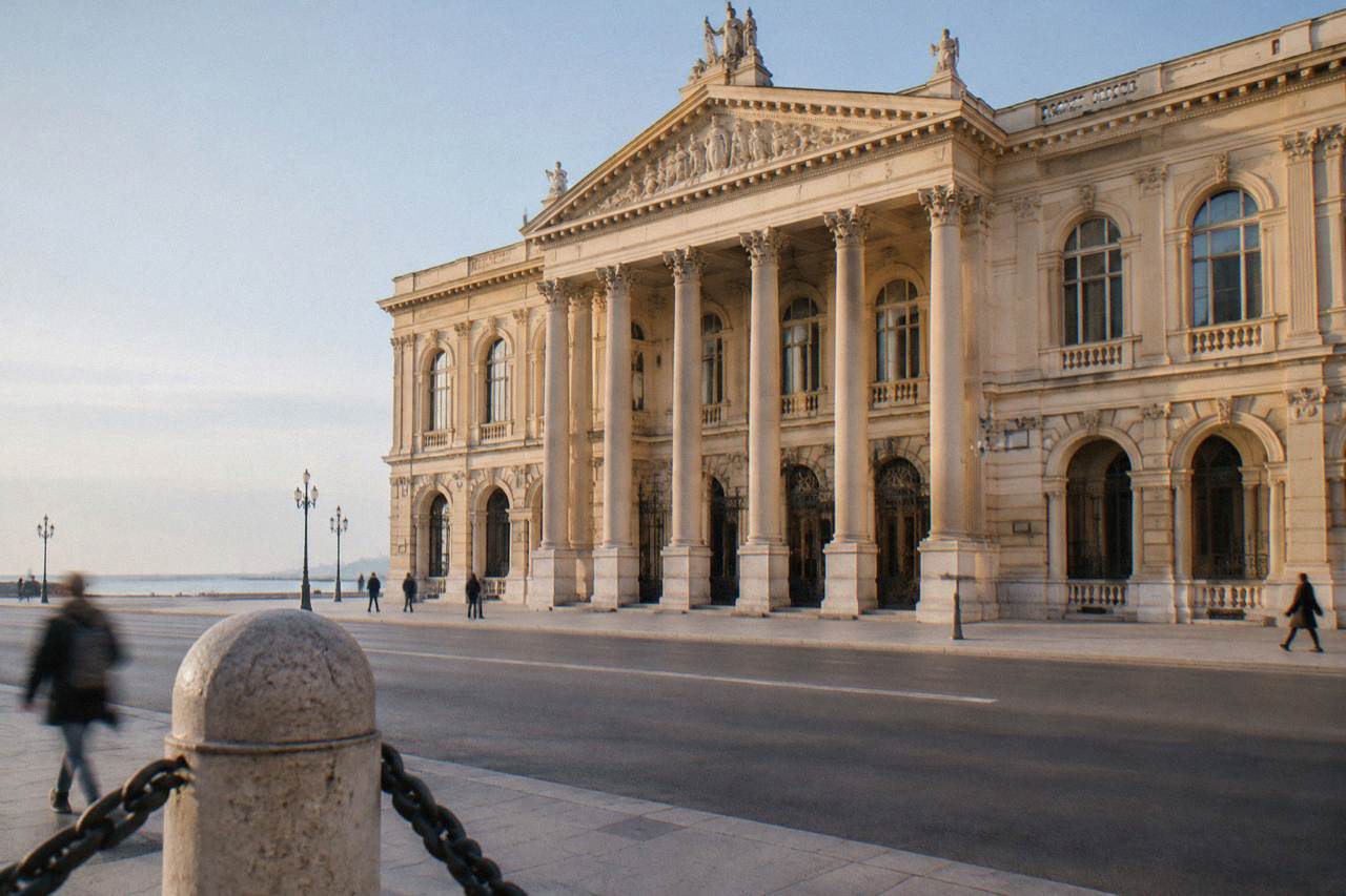 Grand neoclassical opera house with a cream facade, a columned portico and tall arched windows on a wide street