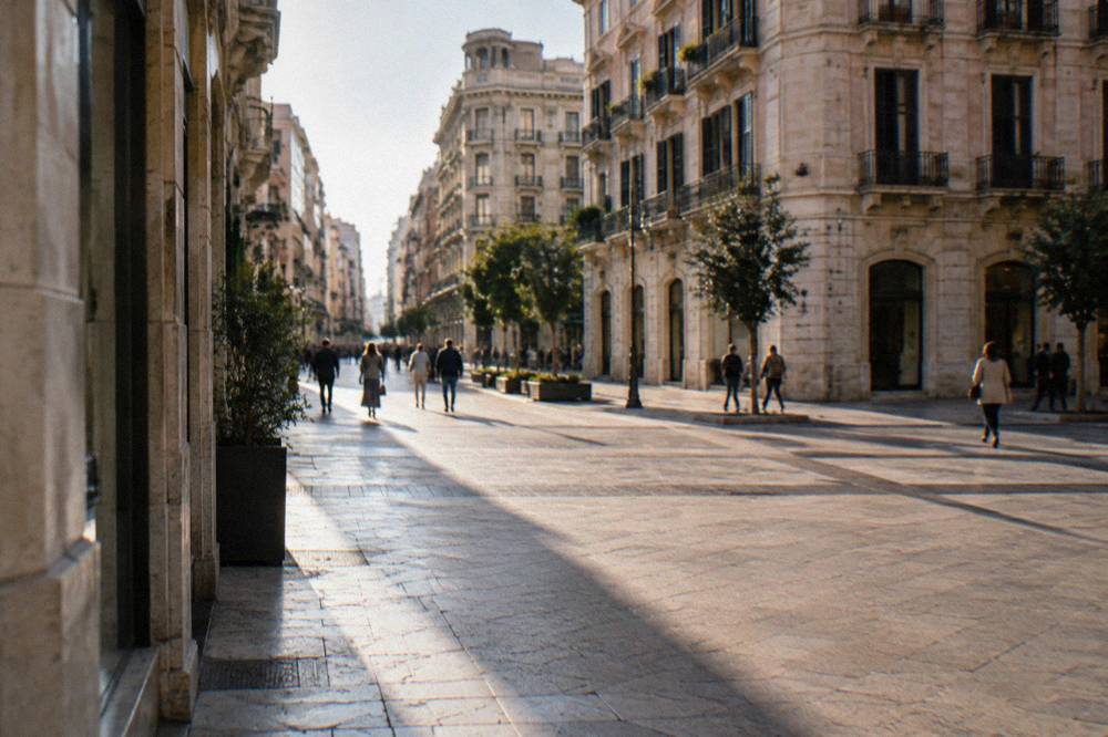 Shoppers far off crossing the paved intersection of a pedestrian street between tall facades