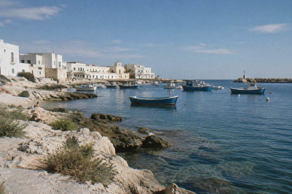 Former fishing hamlet with low whitewashed houses, a small harbour with moored boats and a rocky shore