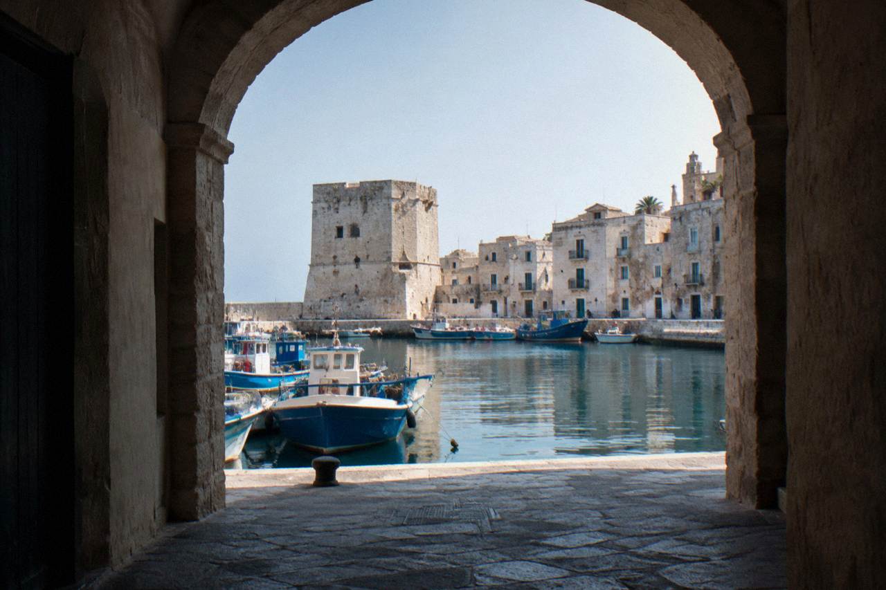 Small harbour of fishing boats under the pale walls of an old town with a squat stone tower