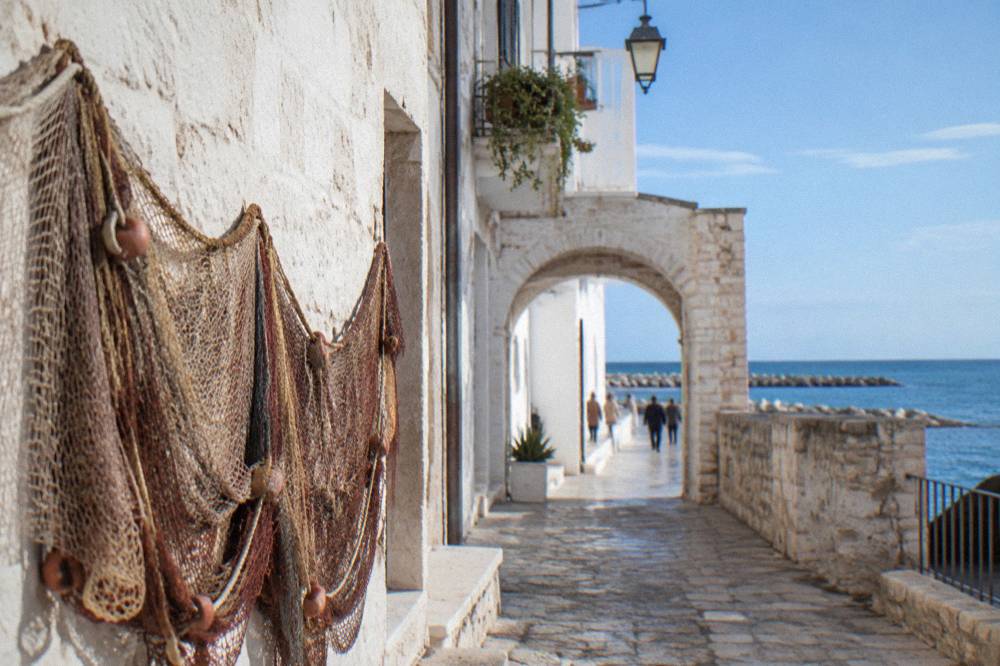 Quiet old town lane with whitewashed walls, an archway and a fishing net hung to dry
