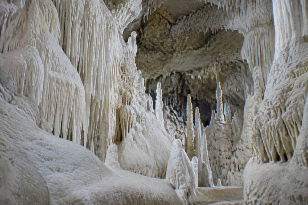 Chamber of pure white alabaster cave formations glowing under soft light