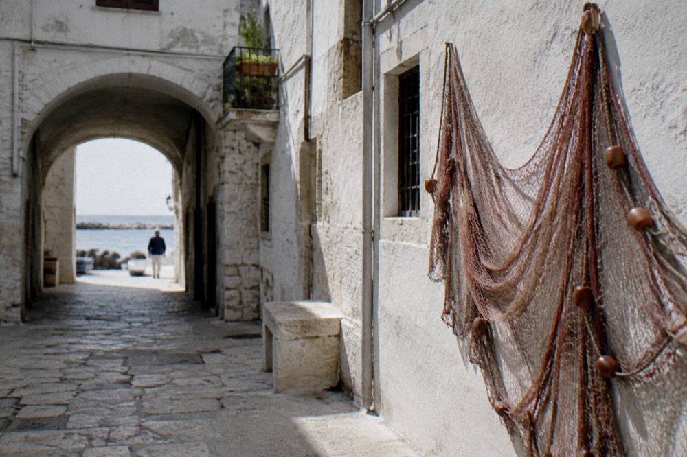 Quiet old town lane with whitewashed walls, an archway and a fishing net hung to dry
