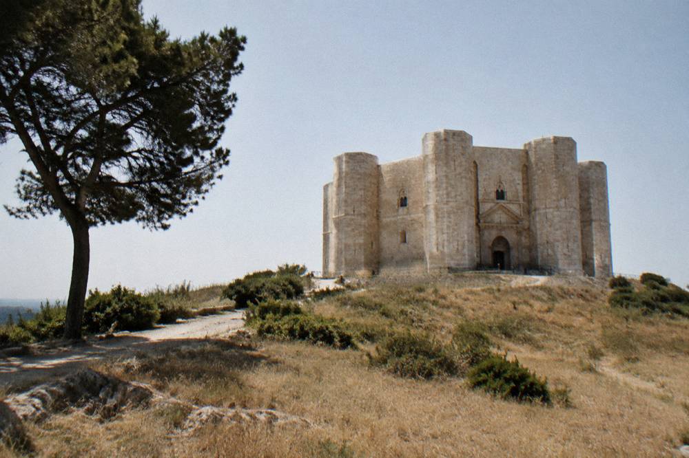 Octagonal pale limestone fortress with eight corner towers alone on a low hill above dry golden fields