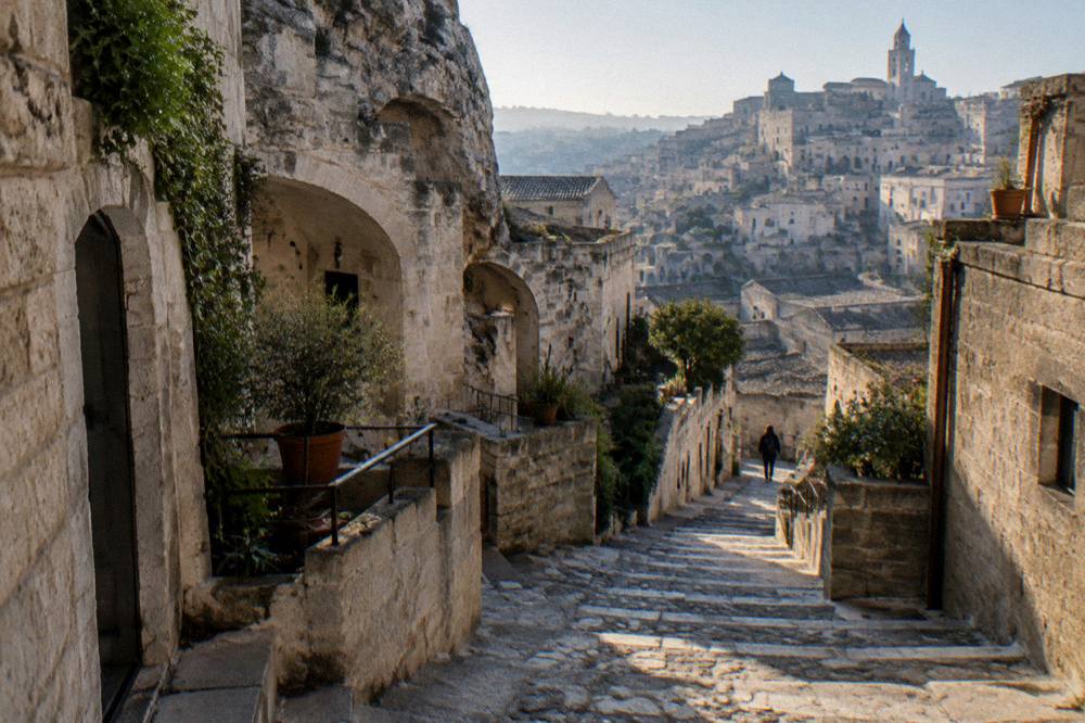 Stepped stone lane among cave houses with arches and small gardens in strong light and deep shadow