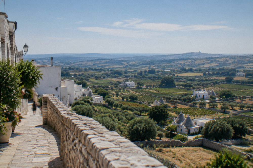 Valley of vineyards, dry-stone walls and conical-roofed farm houses seen from a hill town