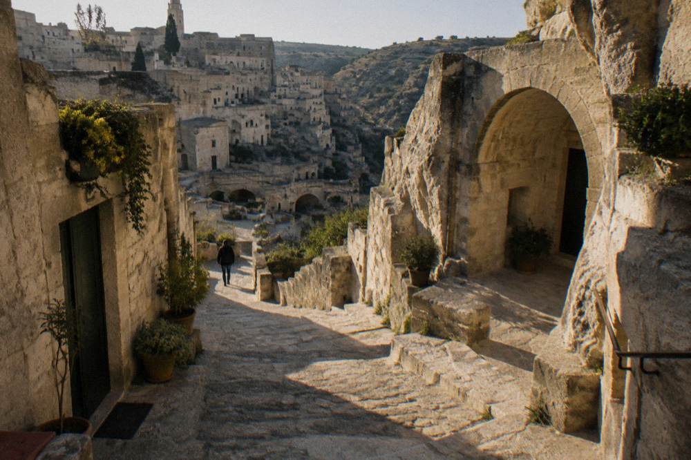 Stepped stone lane among cave houses with arches and small gardens in strong light and deep shadow