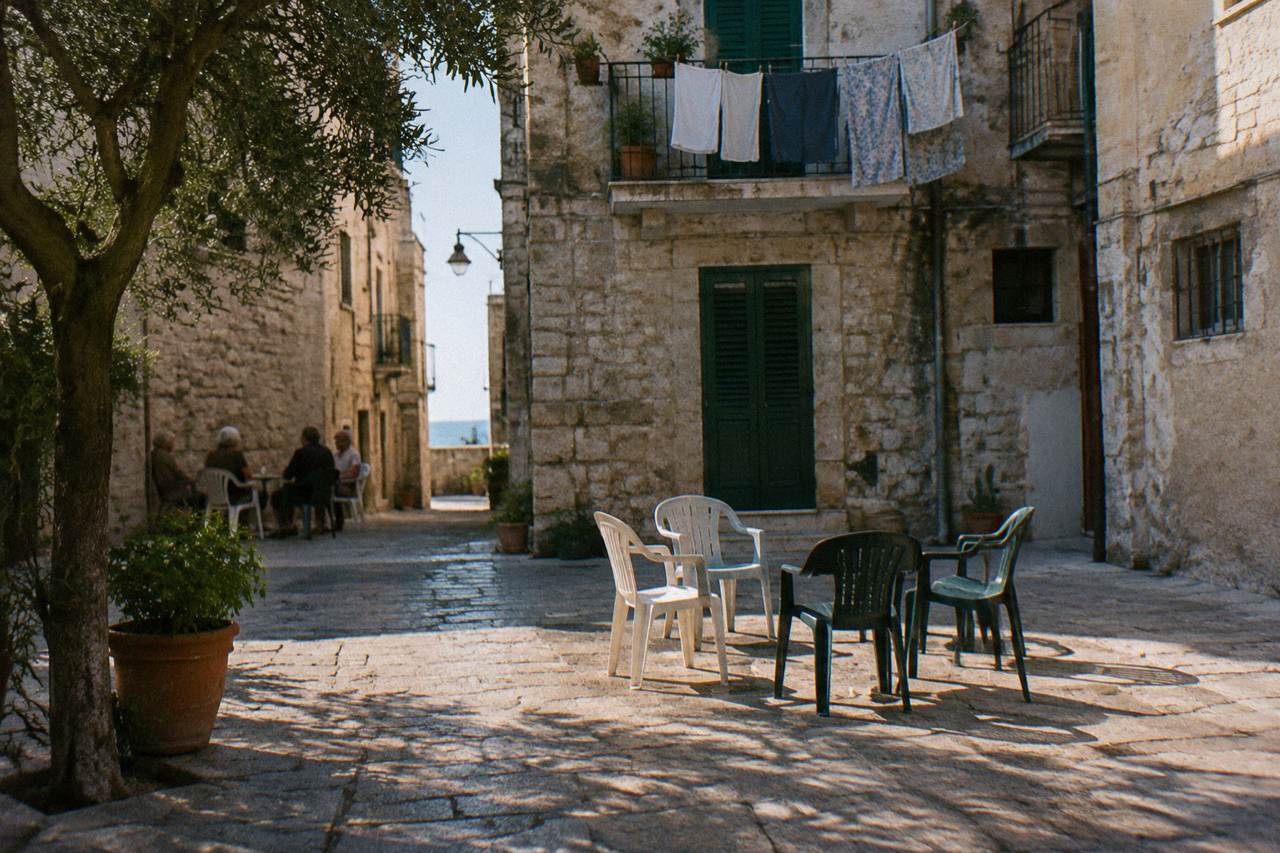 Tiny square where plastic chairs are drawn up in a circle and elderly residents chat far off in the shade