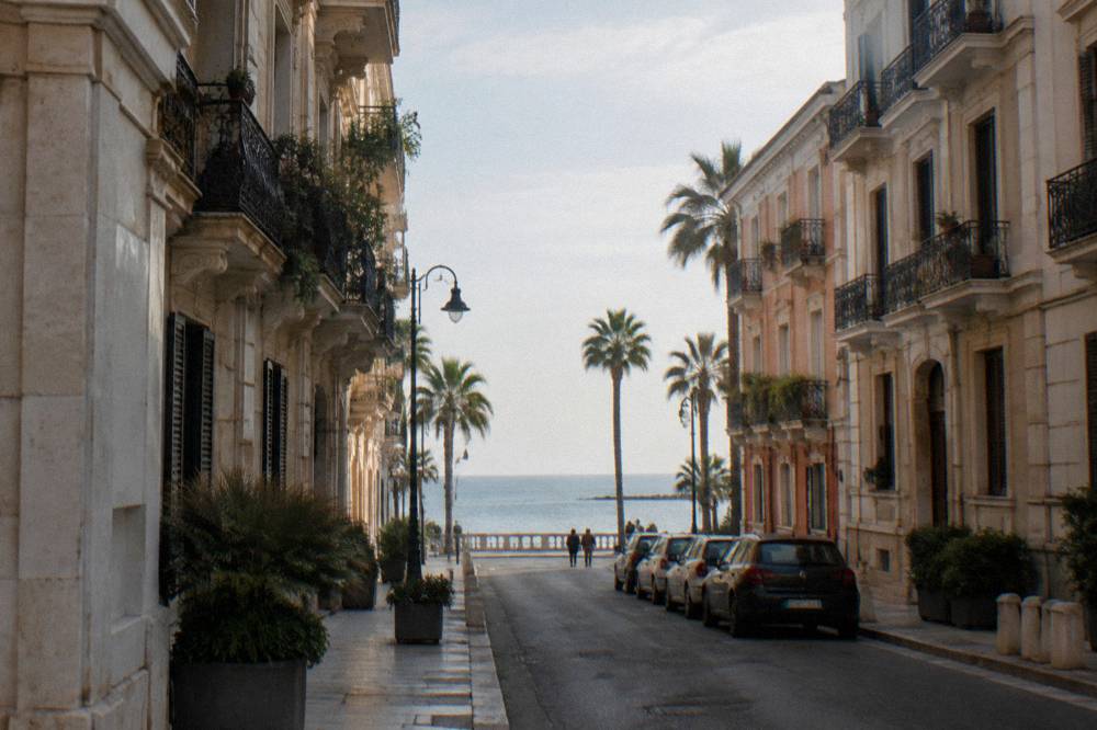 Residential street of Liberty apartment buildings with iron balconies, palm trees and the sea at its end