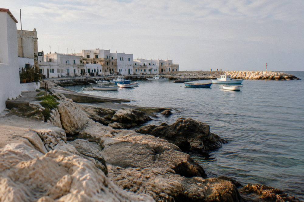 Former fishing hamlet with low whitewashed houses, a small harbour with moored boats and a rocky shore