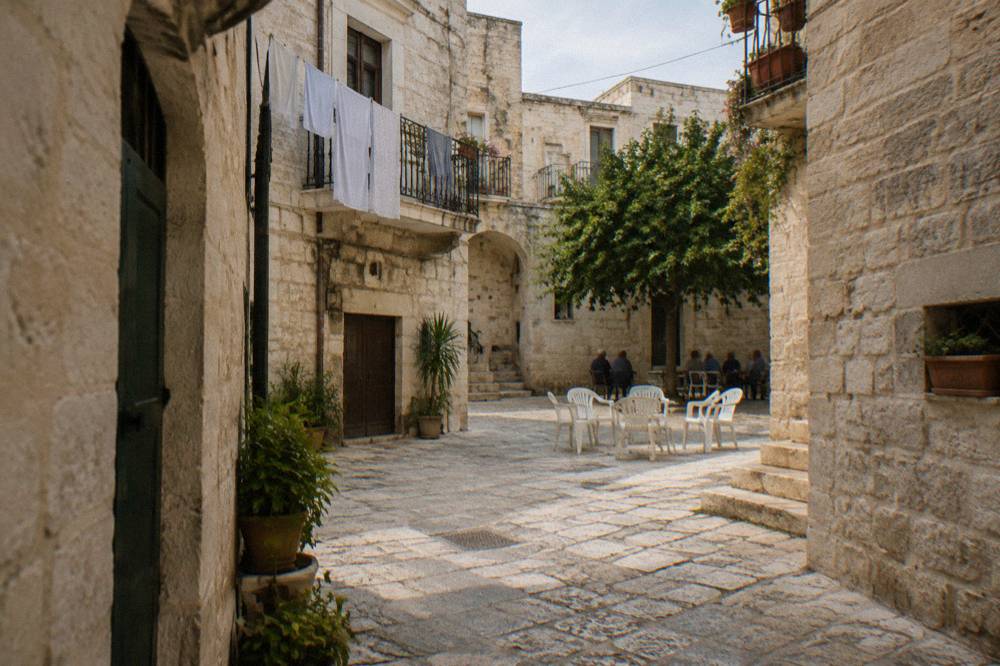 Tiny square where plastic chairs are drawn up in a circle and elderly residents chat far off in the shade