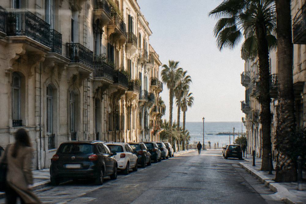 Residential street of Liberty apartment buildings with iron balconies, palm trees and the sea at its end
