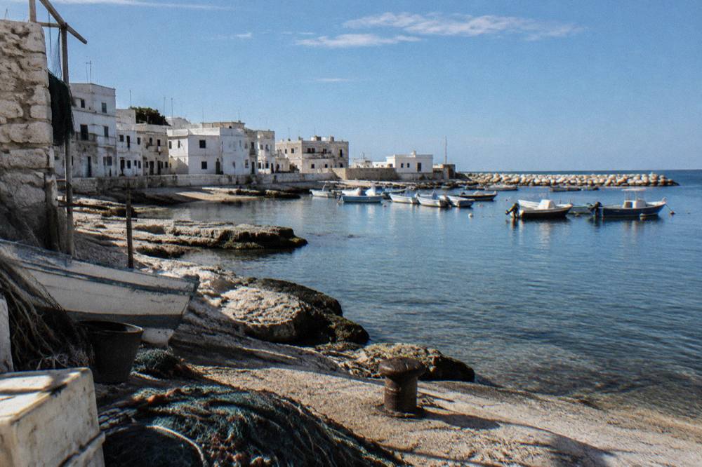 Former fishing hamlet with low whitewashed houses, a small harbour with moored boats and a rocky shore