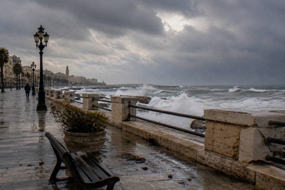 Grey winter sea with white-capped waves breaking against a seafront wall under a heavy sky