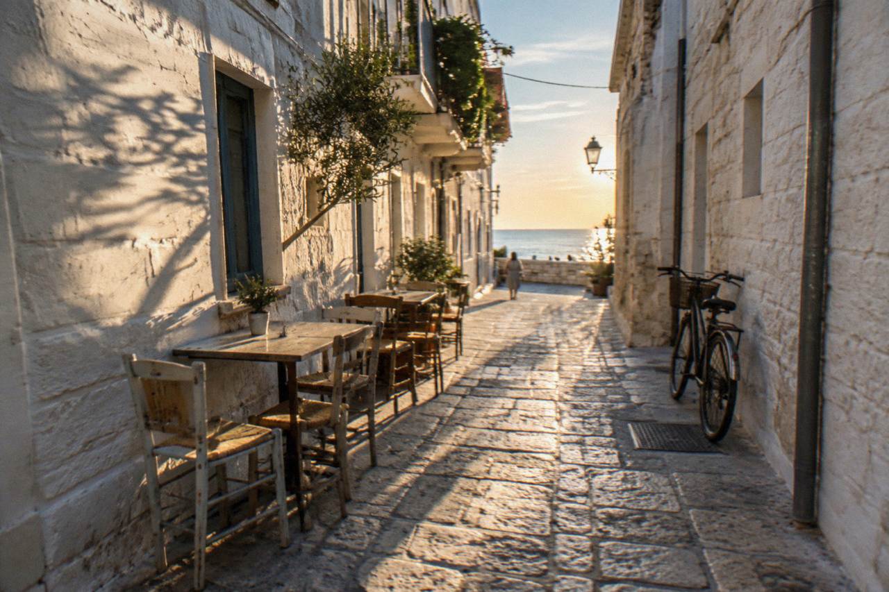 Whitewashed old town lane at midday with chairs and tables against the walls and stripes of sun and shadow