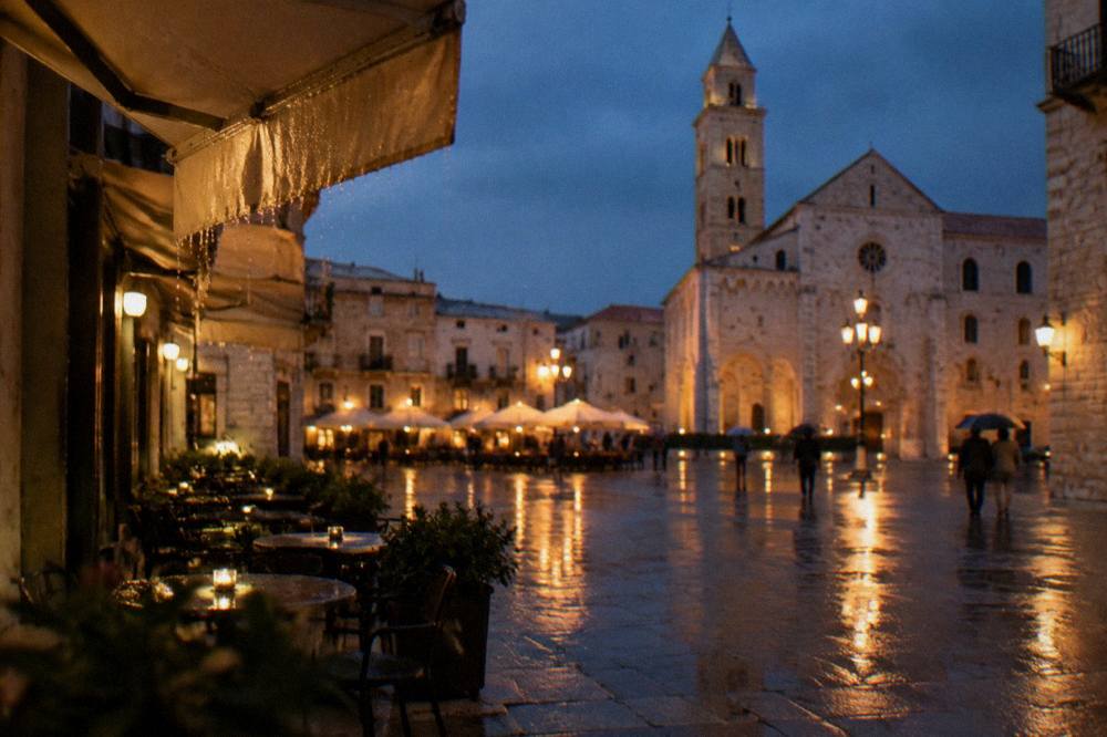 Rainy evening in a pale stone square with wet paving reflecting warm cafe lights and distant umbrellas