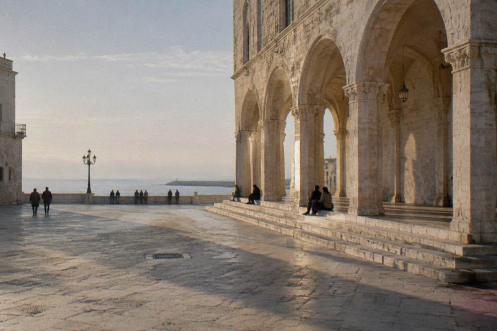 Loggia arches with long afternoon shadows and a few distant people sitting on the steps