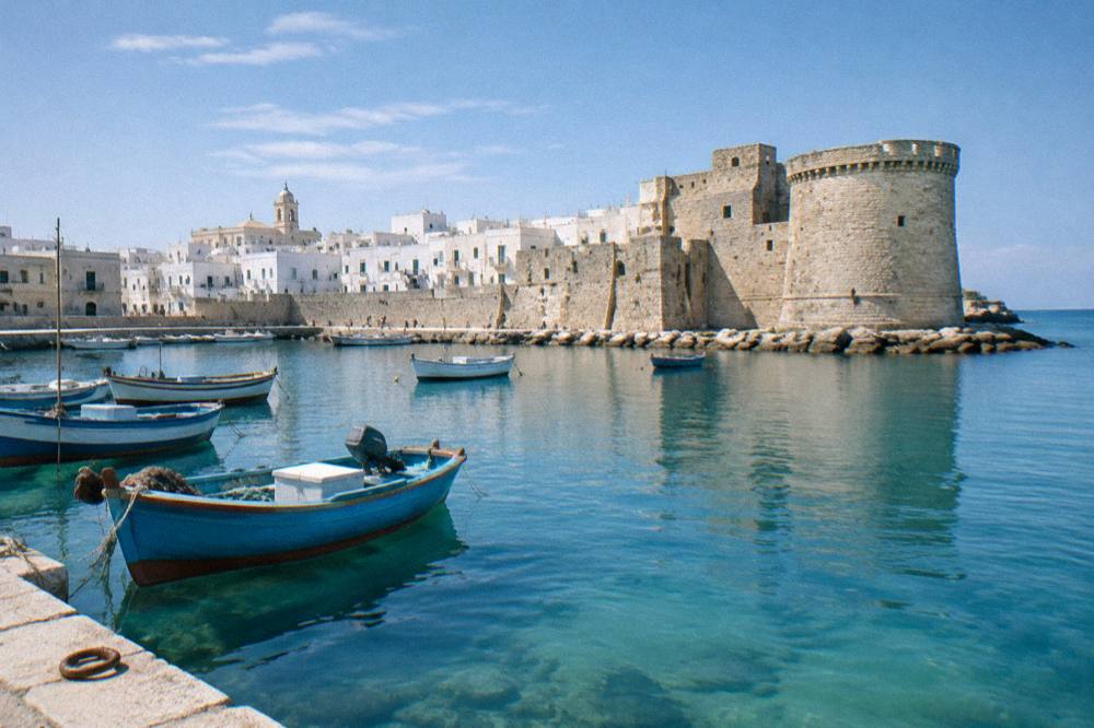 Old harbour of small painted wooden boats with a stone castle on the headland and a whitewashed old town behind