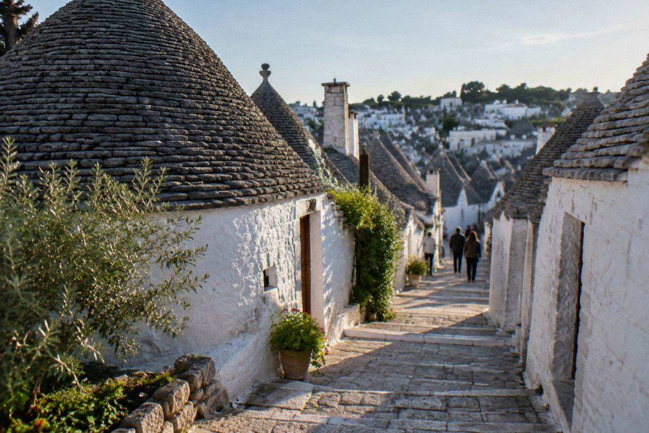 Hillside of white dry-stone houses with grey conical stone roofs and a narrow stepped lane between them