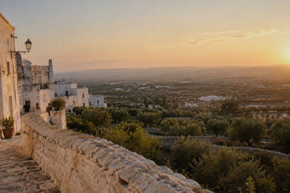 View from a hill town over olive groves and low dry-stone walls to a hazy plain