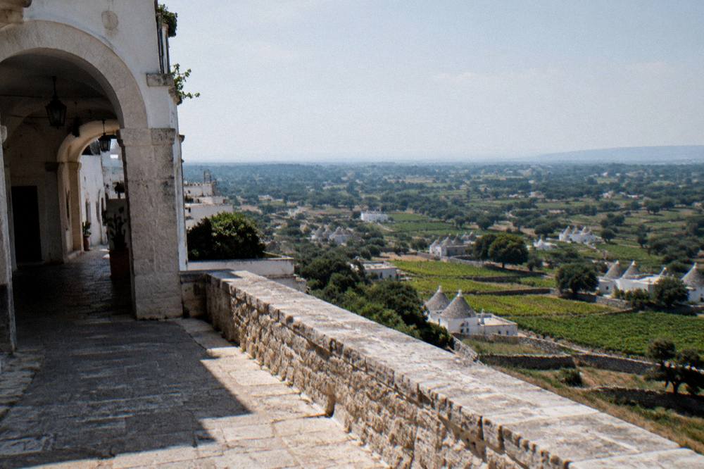 Valley of vineyards, dry-stone walls and conical-roofed farm houses seen from a hill town