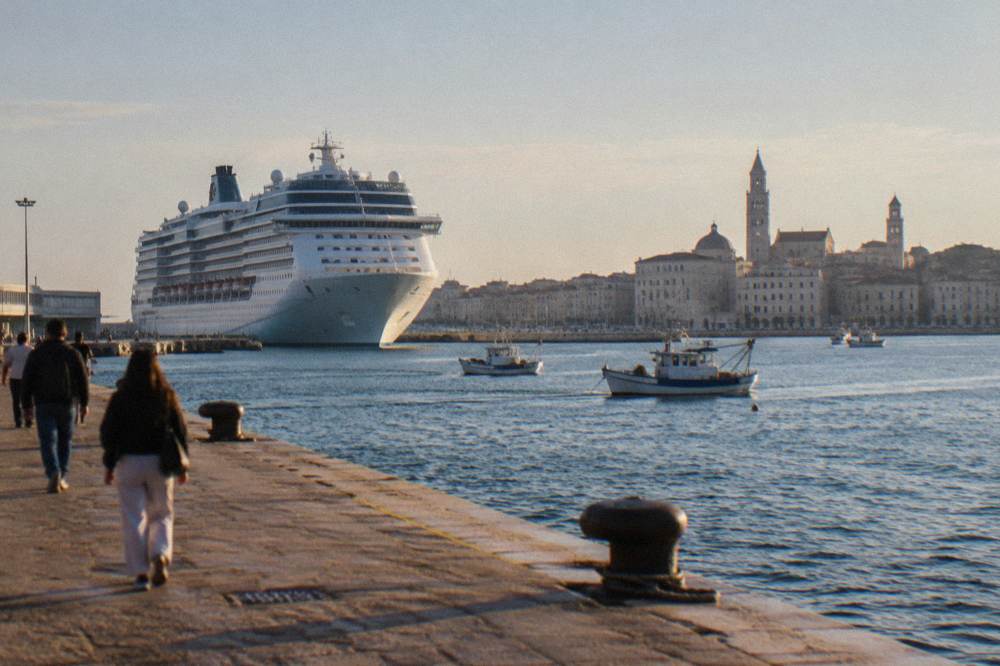 Cruise ship docked beside the pale old town skyline with two towers and small boats in front