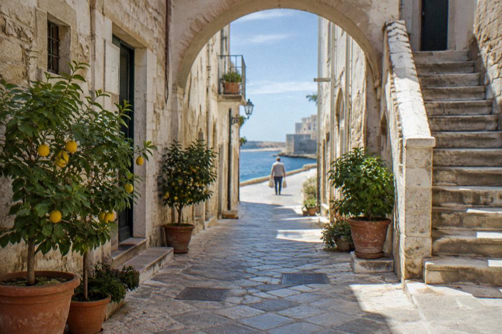 Narrow limestone lane with pale arches, a stone staircase and potted lemon trees in soft morning light