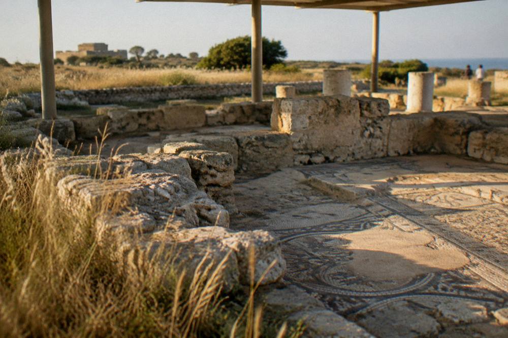 Stone foundations of an ancient basilica with patches of mosaic floor under a light shelter