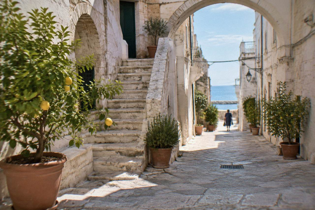 Narrow limestone lane with pale arches, a stone staircase and potted lemon trees in soft morning light