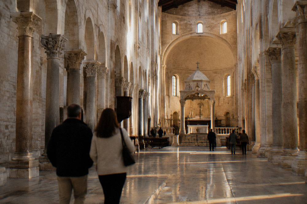 Long stone nave of a Romanesque basilica with simple columns and a raised sanctuary in soft window light