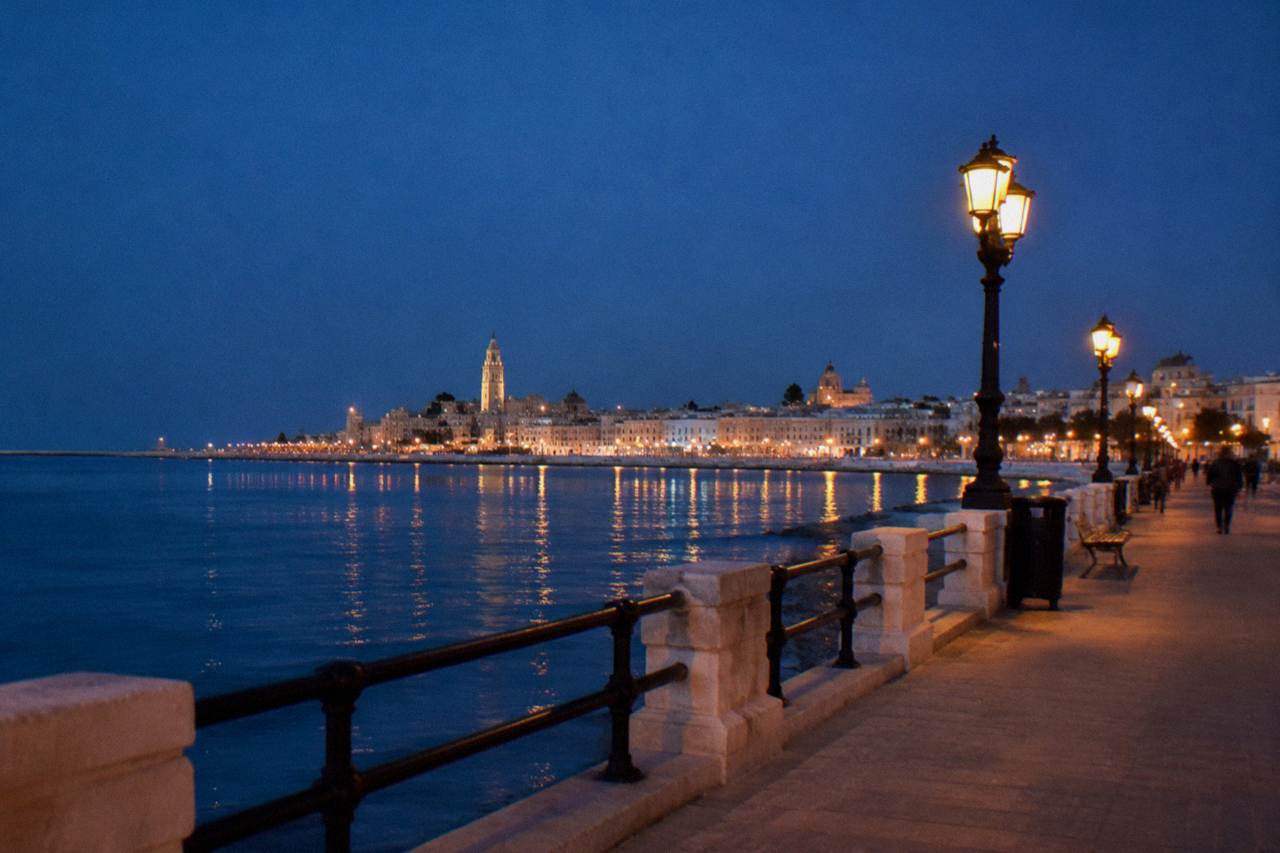 Seafront promenade at blue hour with lit street lamps and the lights of the old town across the bay