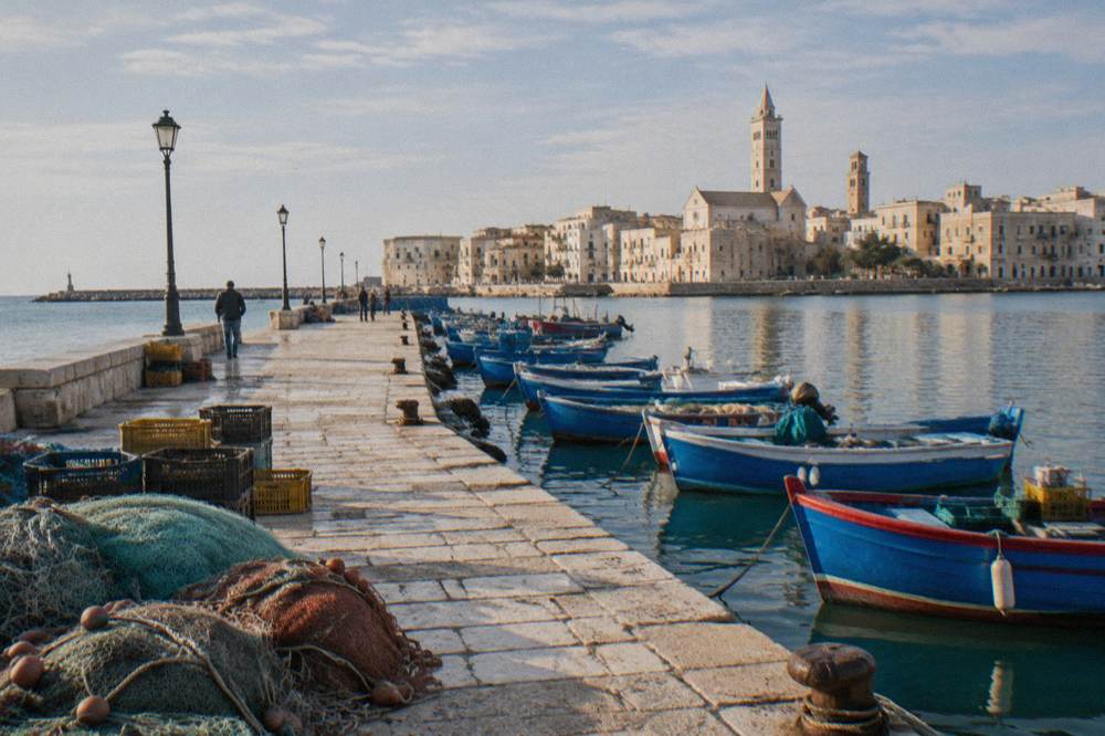 Old harbour pier with small wooden fishing boats, crates and nets and the pale old town skyline with two towers behind