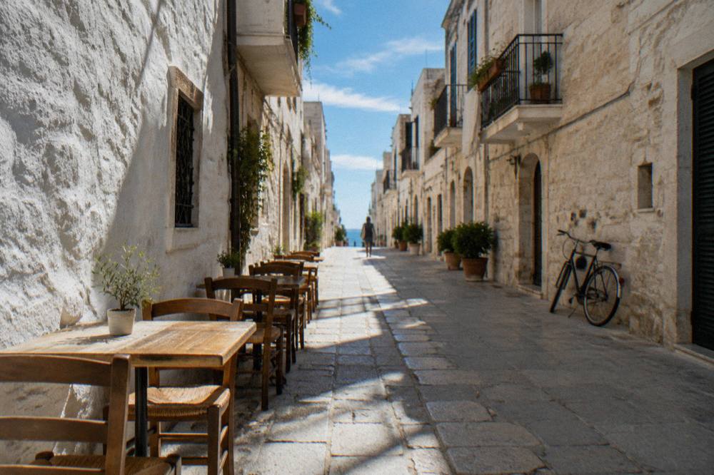 Whitewashed old town lane at midday with chairs and tables against the walls and stripes of sun and shadow