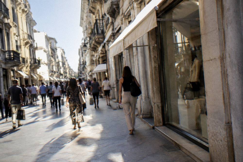 Lively pedestrian shopping street lined with facades with distant shoppers carrying bags