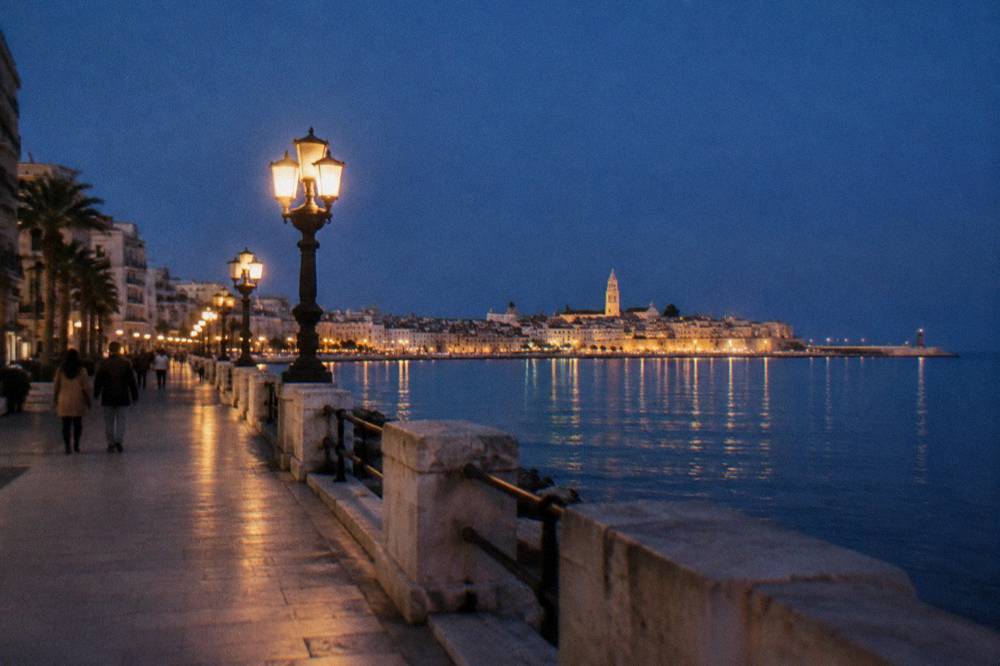 Seafront promenade at blue hour with lit street lamps and the lights of the old town across the bay