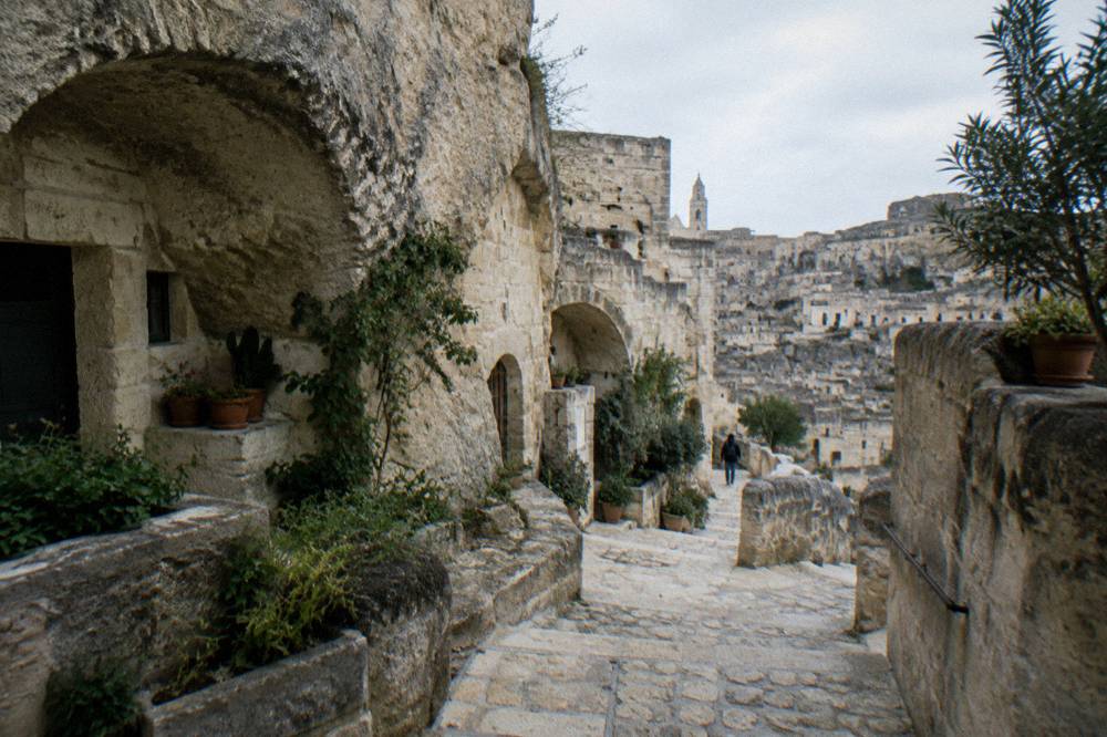 Stepped stone lane among cave houses with arches and small gardens in strong light and deep shadow